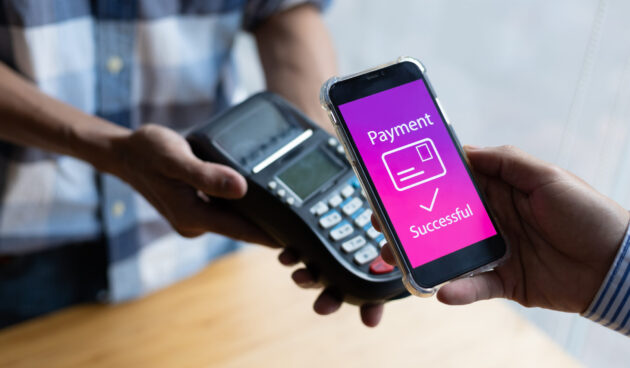Close-up of a customer paying for goods with a mobile app on the counter. Close-up of a customer paying for goods with a mobile app on the counter.