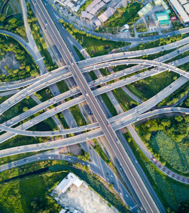 Aerial view of road interchange or highway intersection with busy urban traffic speeding on the road. Junction network of transportation taken by drone.