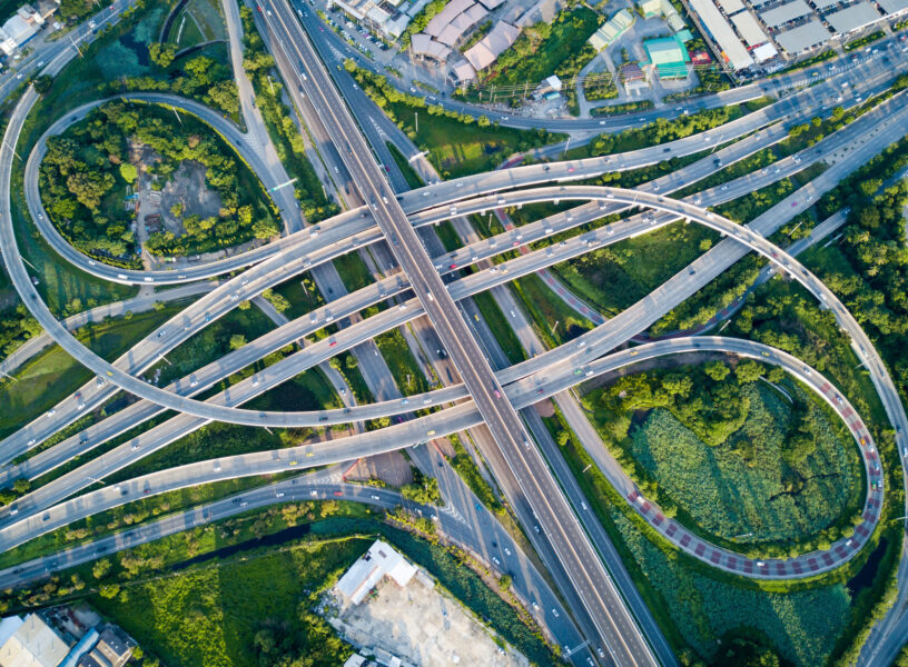 Aerial view of road interchange or highway intersection with busy urban traffic speeding on the road. Junction network of transportation taken by drone.