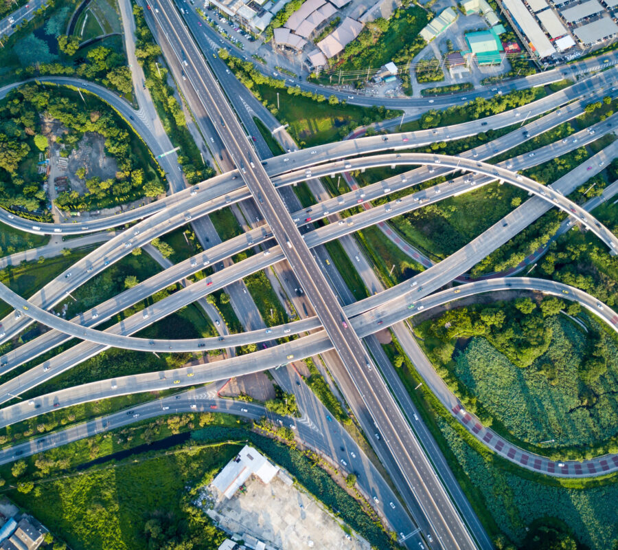 Aerial view of road interchange or highway intersection with busy urban traffic speeding on the road. Junction network of transportation taken by drone.